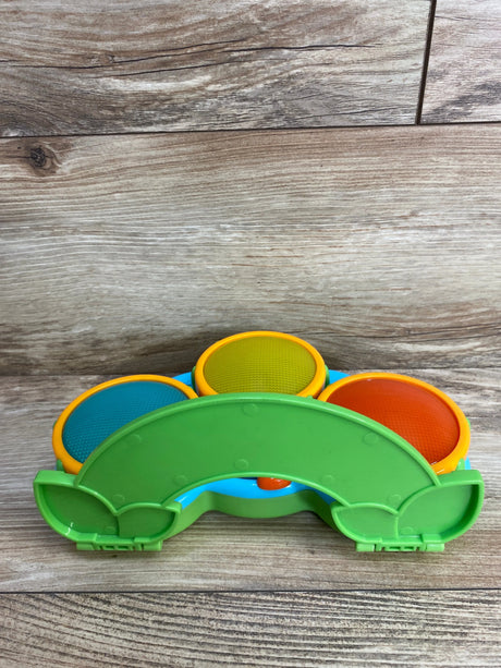 Colorful children's toy drum with blue, yellow, and orange pads on wooden surface