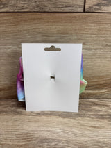 Rear view of large hair bow showing pastel rainbow grosgrain ribbon attached to white retail card on wood background