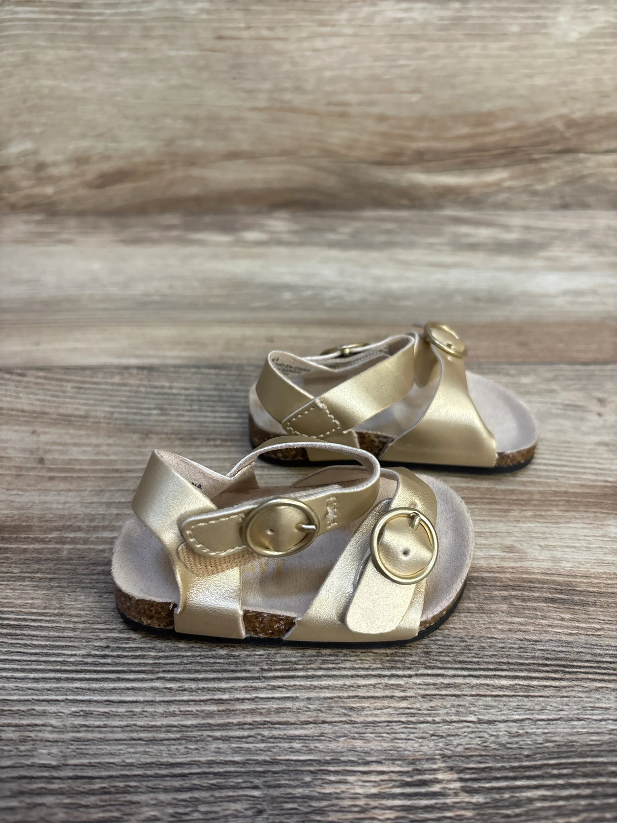 Gold toddler sandals with buckle straps on wooden background, kids footwear resale