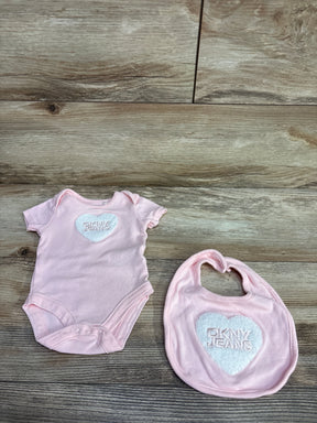 Pink DKNY JEANS baby onesie and matching bib with white heart logo on wooden floor
