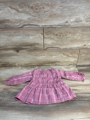 Pink plaid baby dress with smocked bodice and long sleeves on wood floor