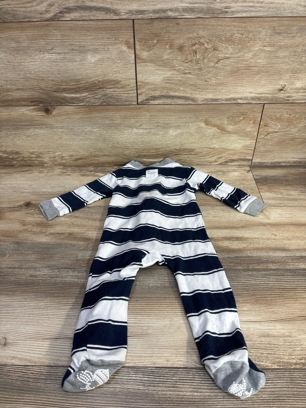 Flat lay of navy and white striped footed sleeper size 6-9 months, back up, gray cuffs and white non-slip foot grips on wood