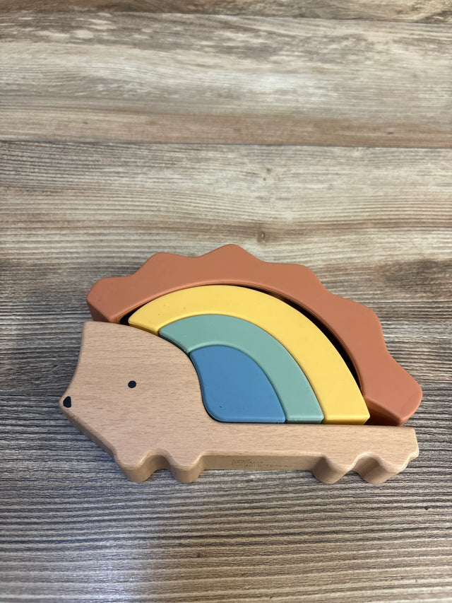 Top-down view of Cloud Island hedgehog stacker with nested silicone rainbow arches in muted colors on a wood surface
