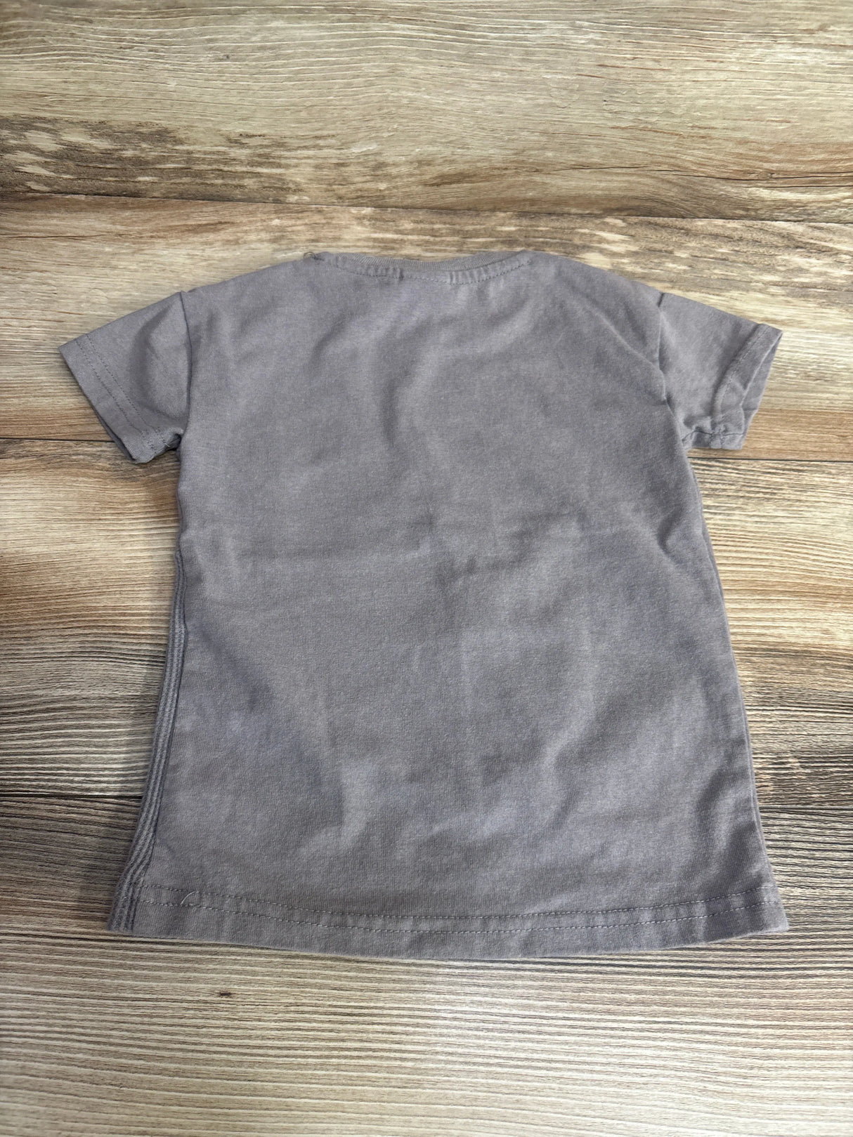 Plain gray short-sleeve toddler t-shirt laid flat on wooden surface, kids resale clothing