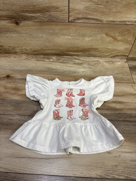 Front view of Cynthia Rowley white flutter sleeve peplum top showcasing nine cowboy boot graphics on a wood floor