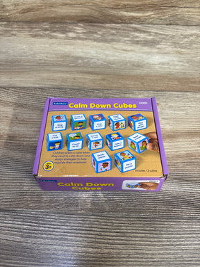 Top view of Lakeshore Calm Down Cubes box showcasing illustrated activity cubes and a hand holding a cube on a wood tabletop