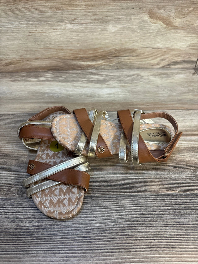 Brown and gold toddler sandals with MK logo, strappy design on wood background