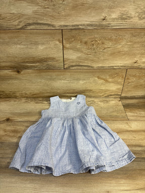 Flat lay of H&M blue linen-blend baby dress with sleeveless bodice, gathered skirt, and embroidered heart on wood background