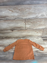 Brown long sleeve toddler shirt laid flat on wood floor background