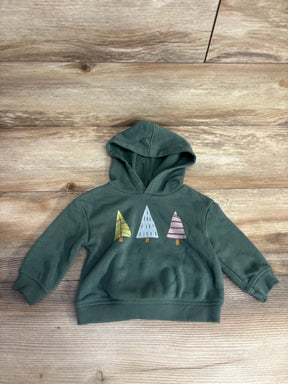 Green kids' hoodie with three colorful tree graphics on wooden background