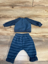 Blue baby boy outfit with long sleeve henley top and striped pants, laid flat on wood floor