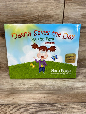 Front cover of hardcover kids' book Dasha Saves the Day: At the Park showing girl on grass and gold signed sticker on wood