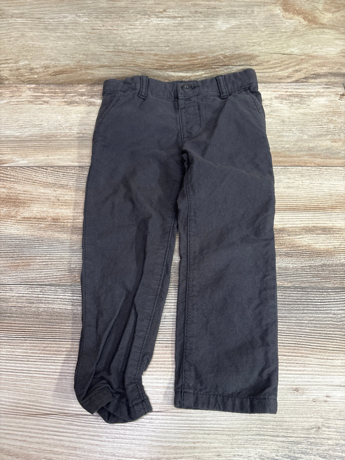 Grey Oshkosh pants for toddlers size 3T laid flat on a light wood background.