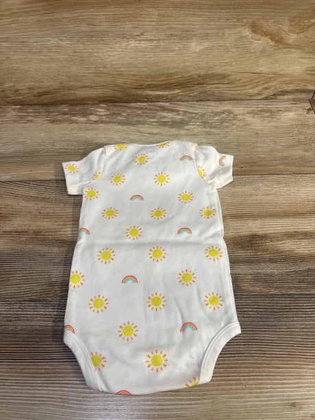 Flat lay of white sun-print baby bodysuit (3-6 months) showing yellow sun and rainbow prints on cotton wood background