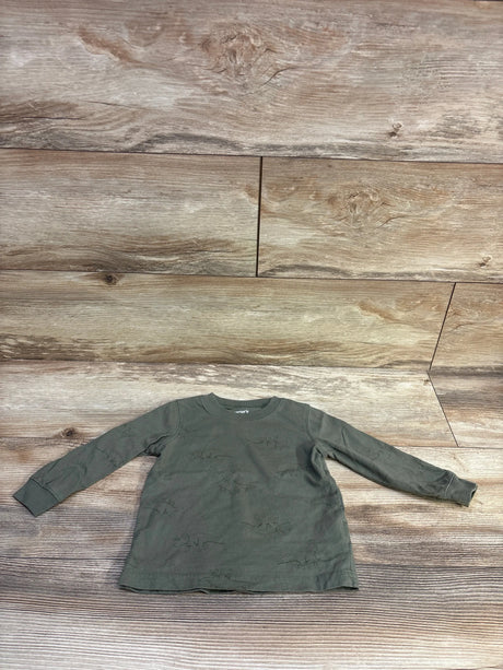 Flat lay of Carter’s green long-sleeve toddler shirt showing faint dinosaur print and crew neck on wood plank background
