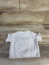Back view of Rarity waffle knit football shirt in beige with short rolled sleeves and waffle texture, laid flat on wood background