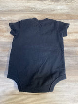 Black short sleeve baby onesie laid flat on wooden surface