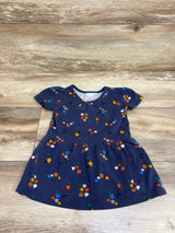 Front view of Hanna Andersson navy floral peplum dress with colorful floral print and gathered skirt on wood background