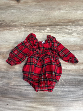 Red plaid baby romper with ruffled sleeves and legs, laid on wood floor