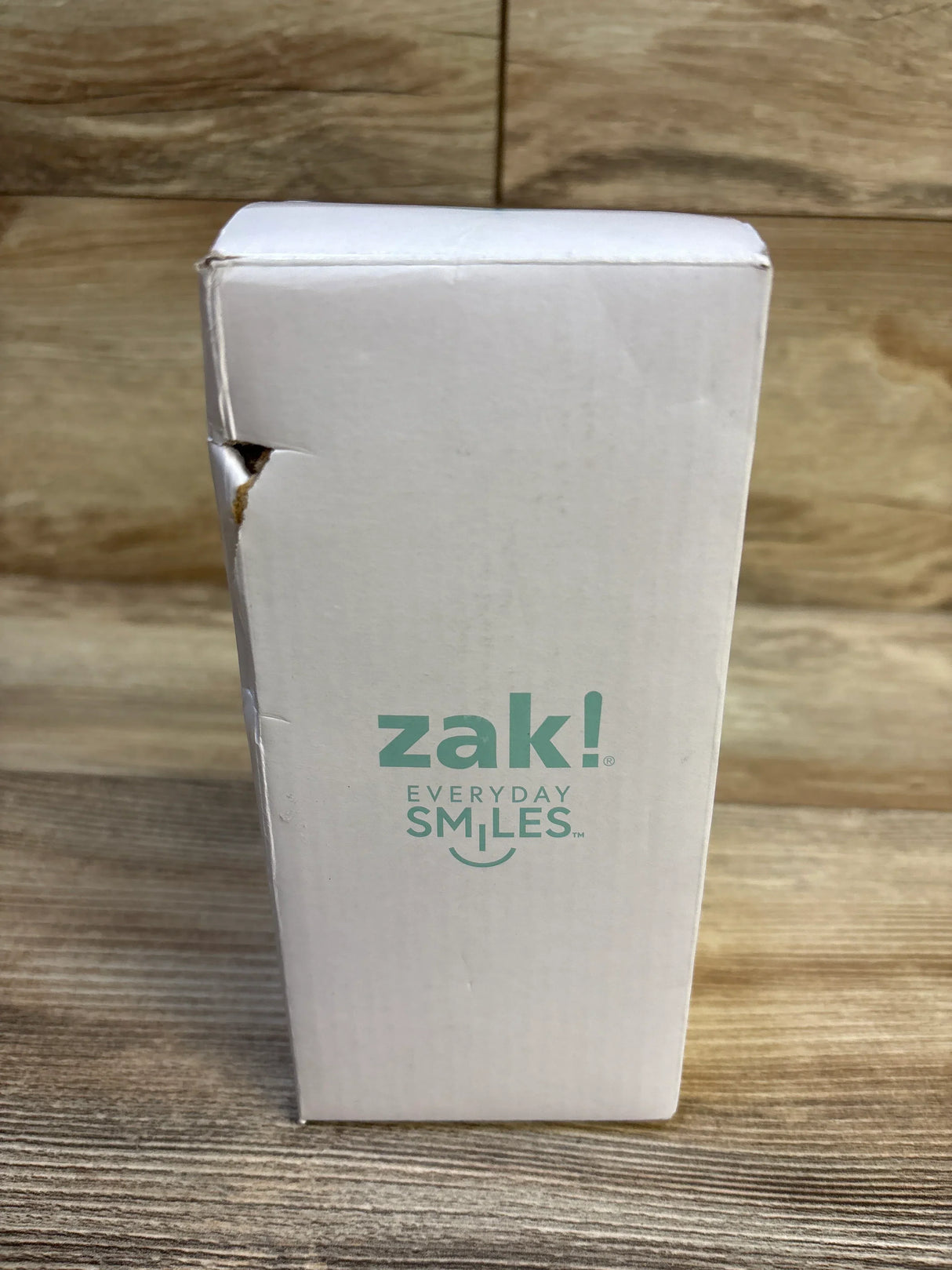 Front view of Zak! Kelso insulated tumbler box showing Zak! logo and torn corner on wood background