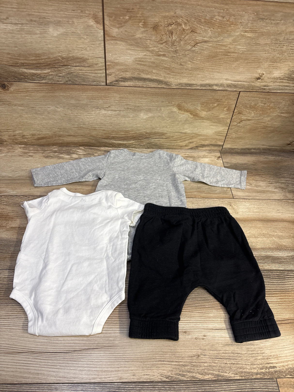 Top-down view of Adidas 3-piece bodysuit set with gray long-sleeve and white short-sleeve bodysuits plus black pants