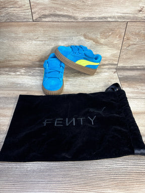 Blue and yellow Puma Fenty toddler sneakers with black Fenty dust bag on wood floor