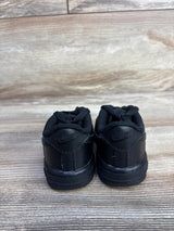 Back view of Nike Air Force 1 06 TD Triple Black Sneakers showcasing all-black leather heel with embossed Nike logo on wood plank floor