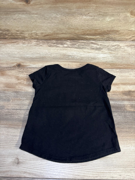 Back view of black toddler Halloween ghost shirt showing plain back and slightly curved hem on wood floor background