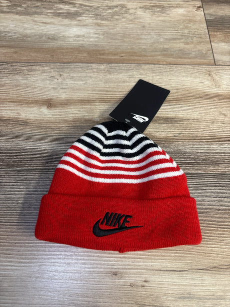 Top-down view of red Nike toddler beanie with black embroidered logo and black-and-white striped crown on wood surface