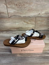 Three quarter view of black Flexmas toddler sandal showcasing rhinestone butterfly straps on a pink shoebox and wood floor