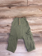 Flat lay of Old Navy olive green sleeveless henley jumpsuit with wooden buttons, chest and cargo pockets on wood floor
