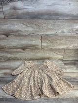 Tan floral baby dress with ruffles and long sleeves on wood floor