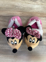 Pair of pink children's slippers with Minnie Mouse faces and polka dot bows on wooden floor