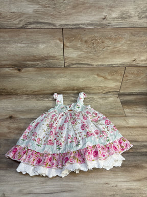 Pink floral baby dress with ruffles and lace trim, laid on wood floor