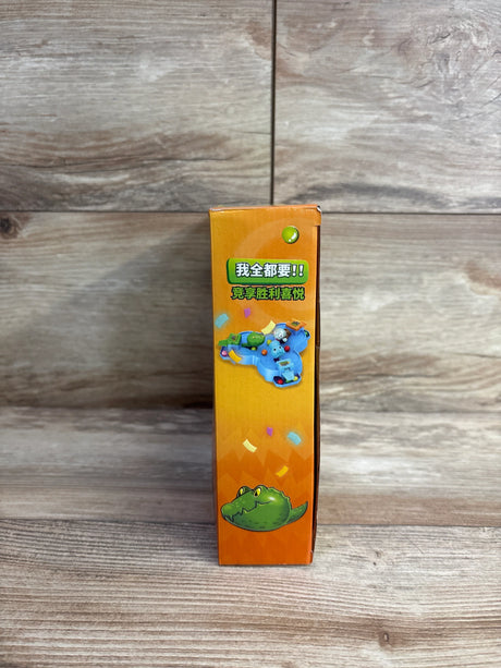 Side view of orange children's toy box featuring cartoon crocodile and colorful game illustration