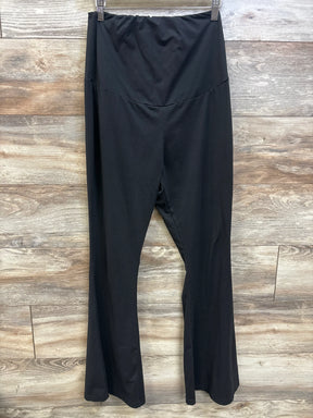 Front view of black maternity flared leggings in size Large, showcasing an over-belly waistband and flared legs on a wood background