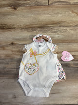 Top-down view of white newborn bodysuit with matching leopard-print ruffle shorts and leopard headband, bodysuit has gold chain and heart leopard-print design on wood background