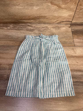 Flat lay of blue and white vertically striped toddler pants with elastic ruffled waist and drawstring on wood floor