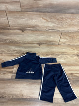 Navy blue Adidas toddler track jacket and pants set with white stripes, laid on wooden floor