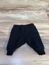 Flat lay of newborn black H and M drawstring joggers showing elastic waistband and ribbed ankle cuffs on wood floor background