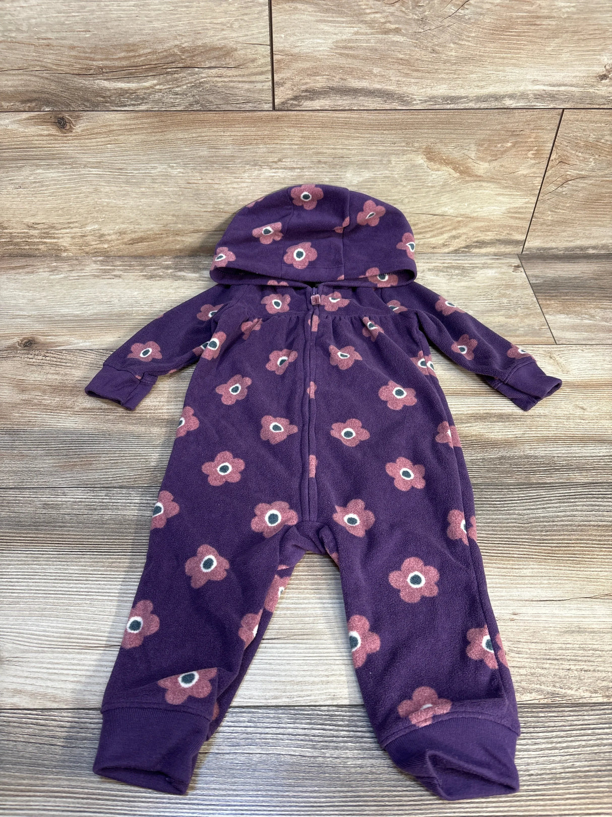 Purple hooded baby romper with pink flower print, laid flat on wood floor