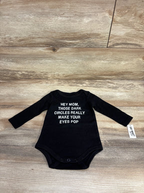 Black long sleeve baby bodysuit with funny text for moms, laid flat on wood background