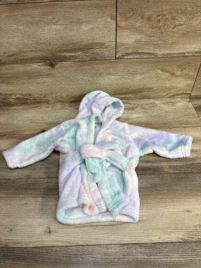 Soft pastel-colored hooded baby bathrobe with belt on wooden floor background