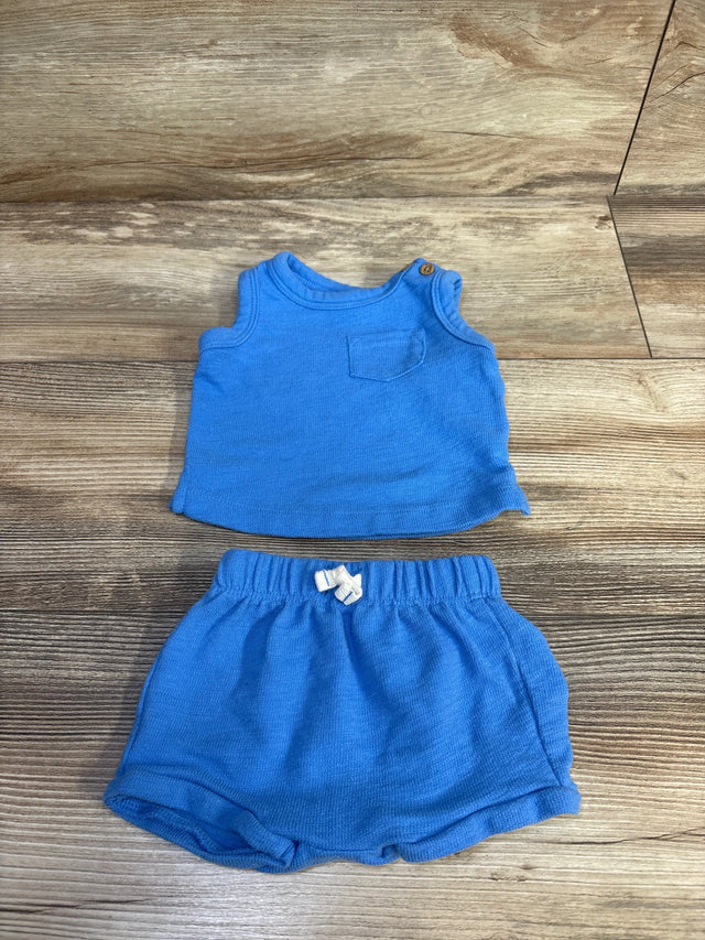 Top-down view of Carter's newborn blue tank top and shorts set showcasing front pocket and elastic drawstring waist on wood background