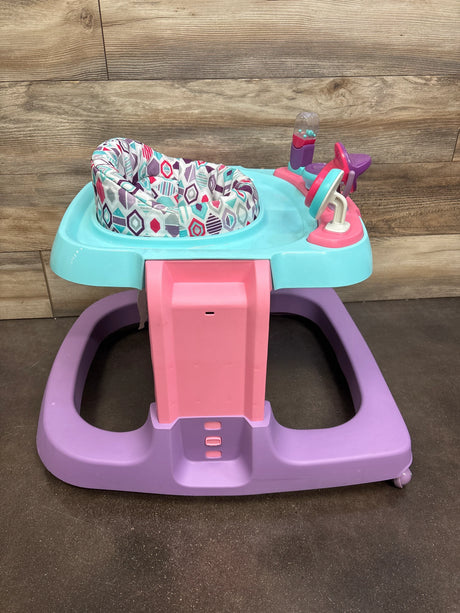 Front view of Safety 1st Ready, Set, Walk DX developmental walker in Lavender Buzz showing patterned padded seat, activity toy panel, and purple base on wood background