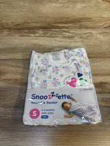Front view of NEW Cribs For Kids Snoozzzette Wearable Blanket in white size 0-6m showcasing sealed packaging with safe sleep print labels on wood plank floor