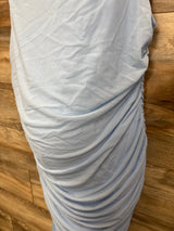 Light blue maternity dress with ruched side detail, soft fabric on wooden floor