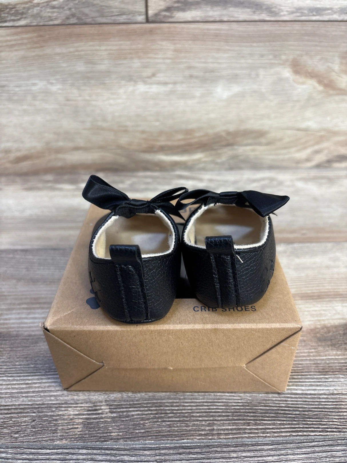 Black baby crib shoes with bows, soft sole, on box