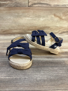 Navy blue toddler sandals with bows and espadrille soles on wood background
