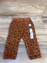 Flat lay of toddler brown leopard print jogger pants showing elastic waistband with drawstring, cuffed ankles, and 12M size tag on wood background